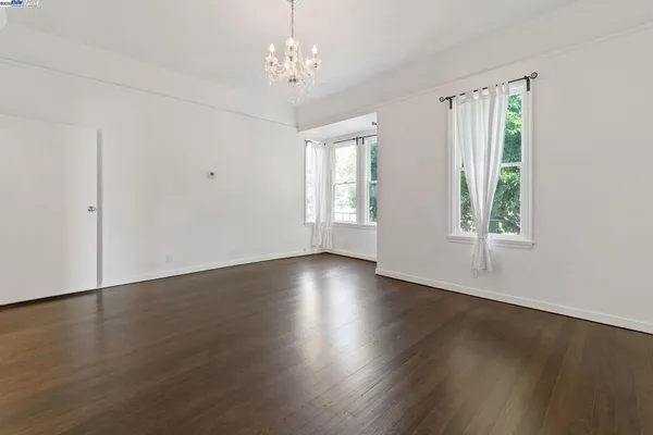 an empty room with wooden floor closet and windows