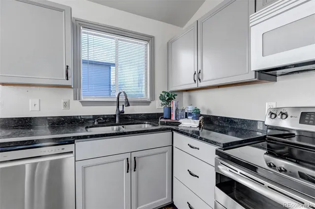 a kitchen with granite countertop white cabinets and white appliances