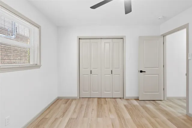 a view of an empty room with window and closet area