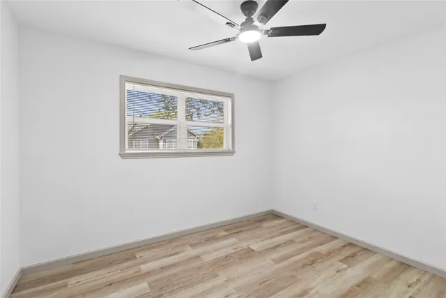 an empty room with wooden floor and fan