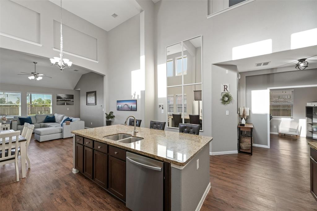 a living room with stainless steel appliances granite countertop a sink dishwasher and a dining table with wooden floor