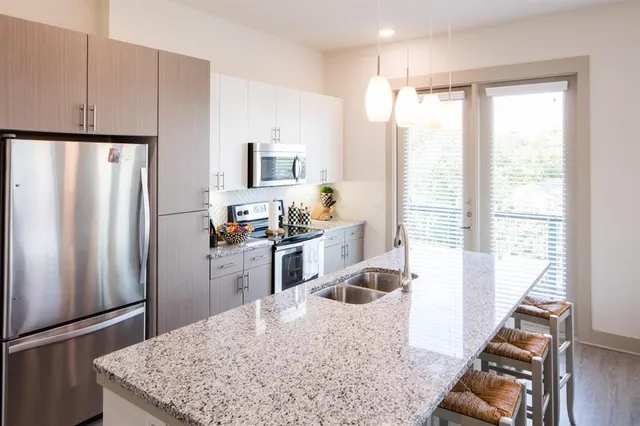 a kitchen with stainless steel appliances granite countertop a refrigerator a sink a stove and a refrigerator