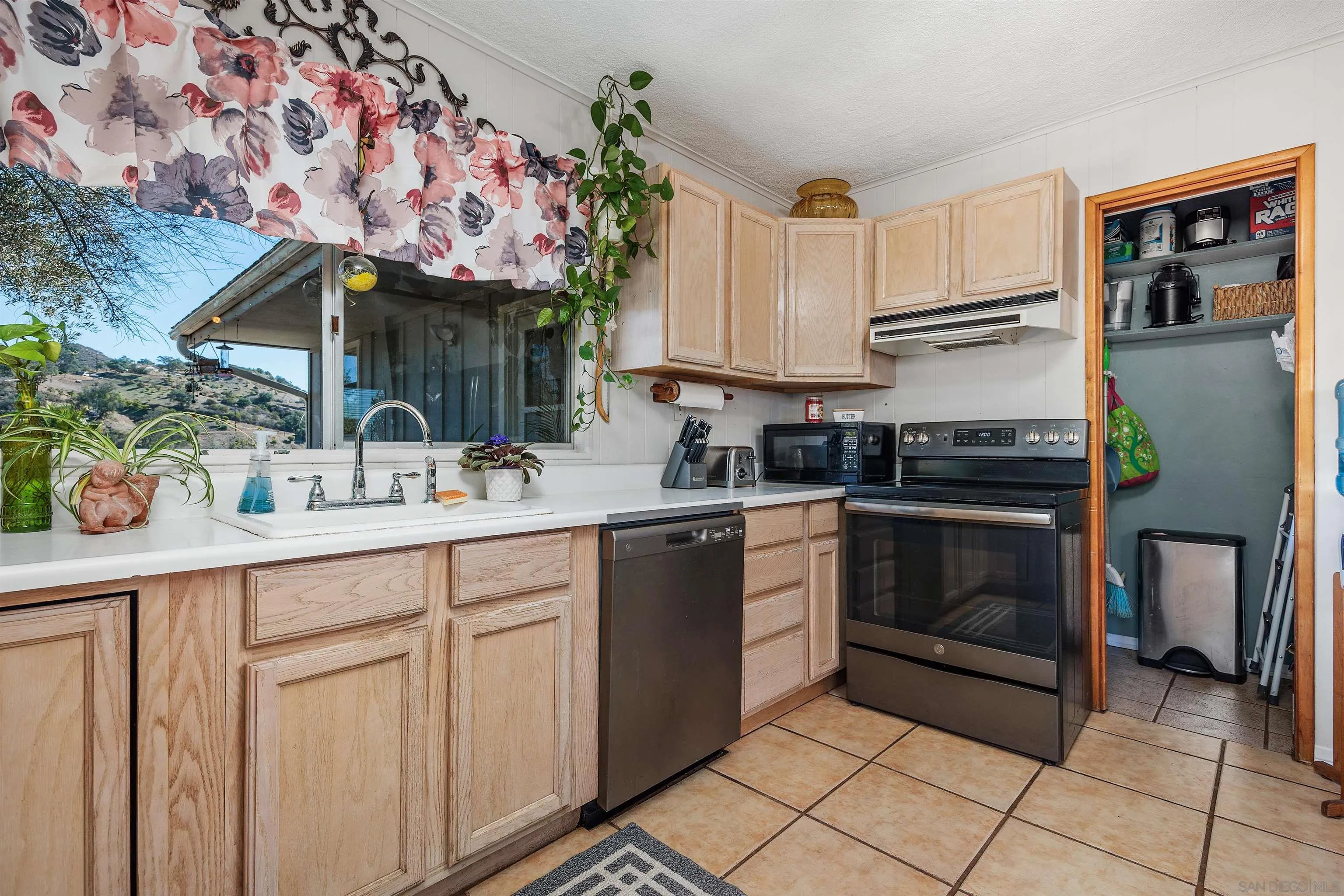 11270 San Luis Rey Drive Valley Center, CA 92082 - Photo 12 of 56 a kitchen with stainless steel appliances a sink cabinets and a window