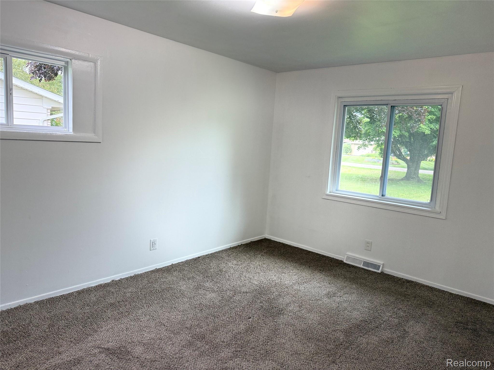 5347 Mapletree Drive Flint, MI 48532 - Photo 8 of 10 Neutral tone interior featuring a large window, a smaller transom window, white painted walls, white trim, and dark carpeting