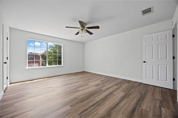 a view of empty room with wooden floor and fan
