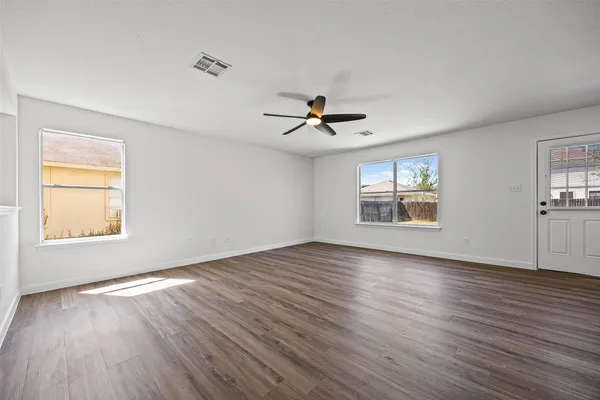 a view of an empty room with wooden floor and a window