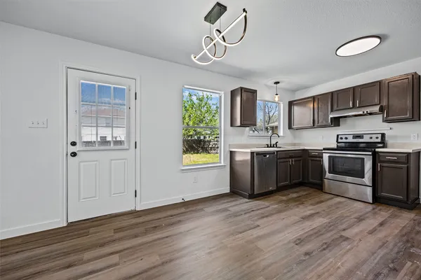a kitchen with stainless steel appliances a sink a stove a refrigerator cabinets and a window