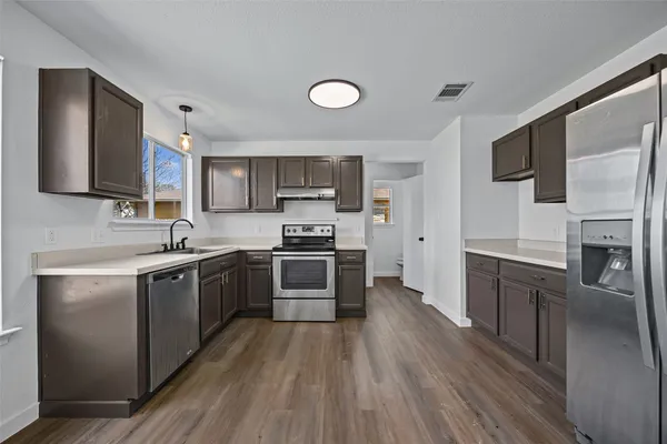 a kitchen with stainless steel appliances granite countertop a stove a sink and a refrigerator