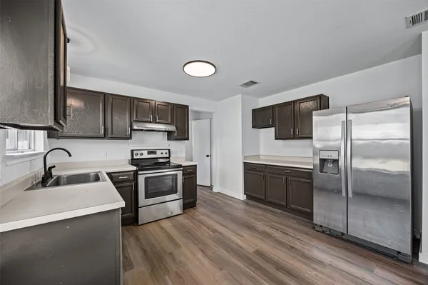 a kitchen with granite countertop a refrigerator stove and sink