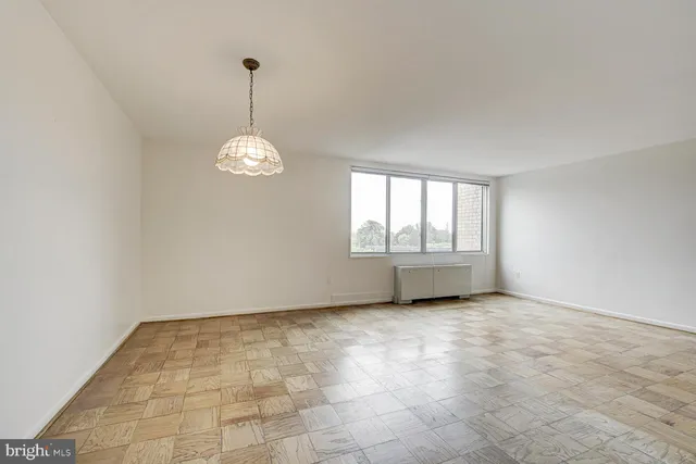a view of an empty room with a window and chandelier fan