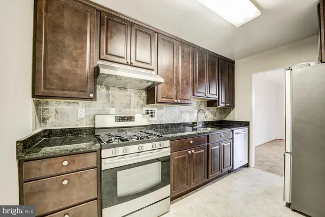 a kitchen with granite countertop wooden cabinets and a stove top oven