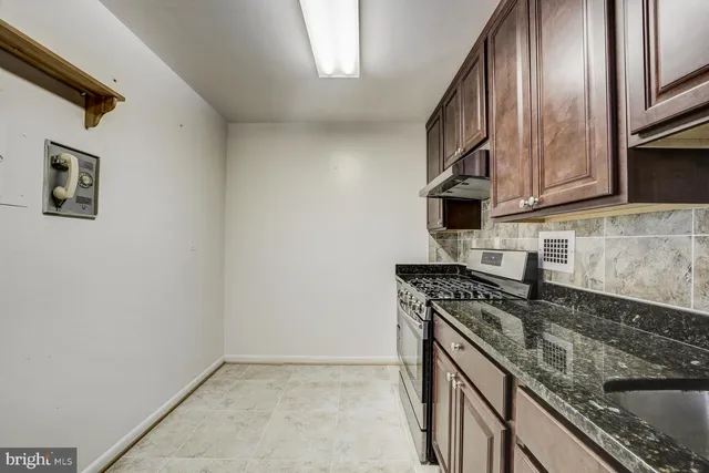 a kitchen with granite countertop a sink stove and cabinets