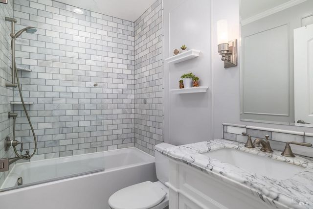 a bathroom with a granite countertop bathtub sink vanity mirror and toilet