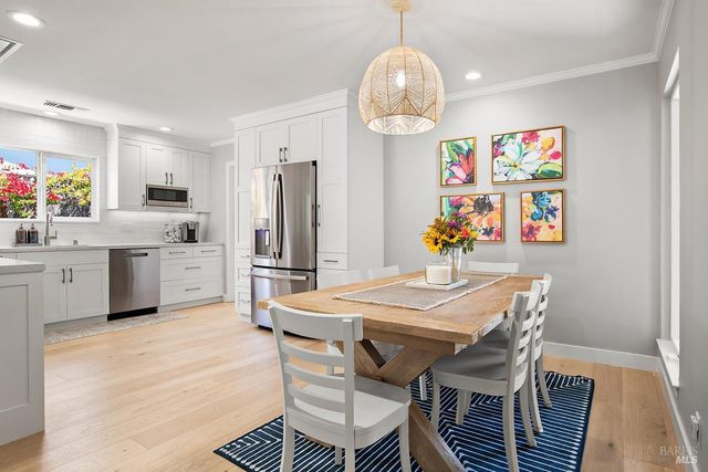 a kitchen with stainless steel appliances granite countertop a sink dishwasher a dining table and chairs with wooden floor