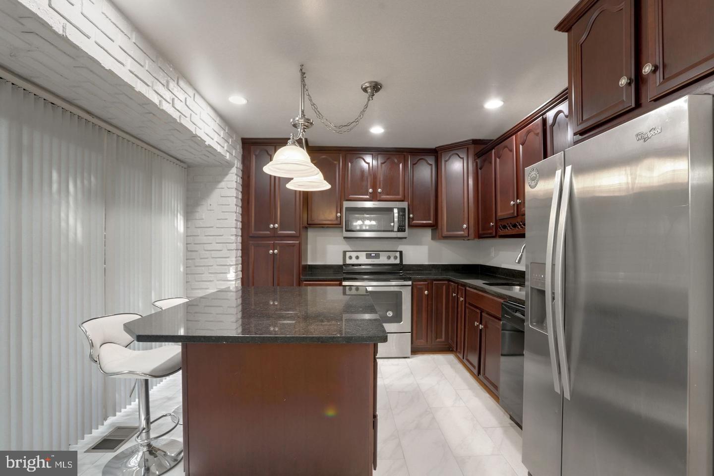 5504 Keppler Road Temple Hills, MD 20748 - Photo 4 of 19 a kitchen with stainless steel appliances granite countertop a refrigerator a sink a stove a microwave and wooden cabinets