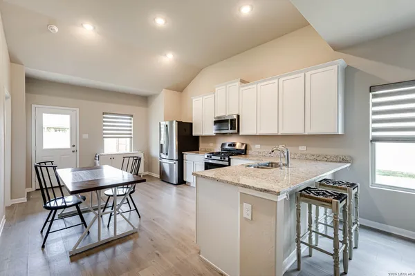 a kitchen with stainless steel appliances granite countertop a table chairs microwave and cabinets