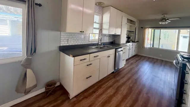 a kitchen with granite countertop a sink cabinets and wooden floor