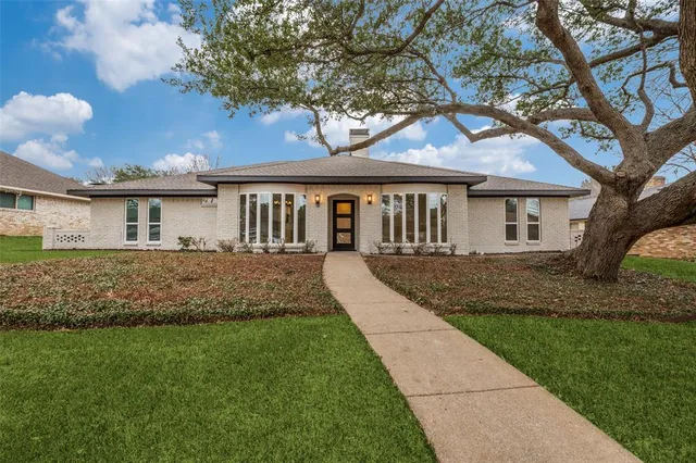 a front view of a house with a garden and trees