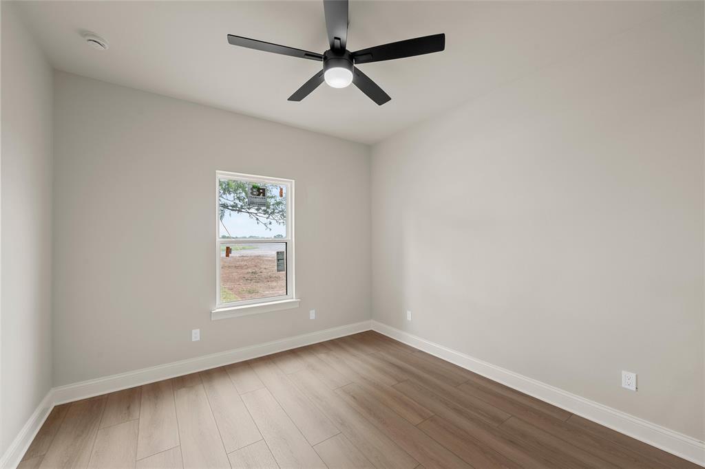 5200 Bogey Lane Waco, TX 76708 - Photo 18 of 37 an empty room with wooden floor ceiling fan and windows
