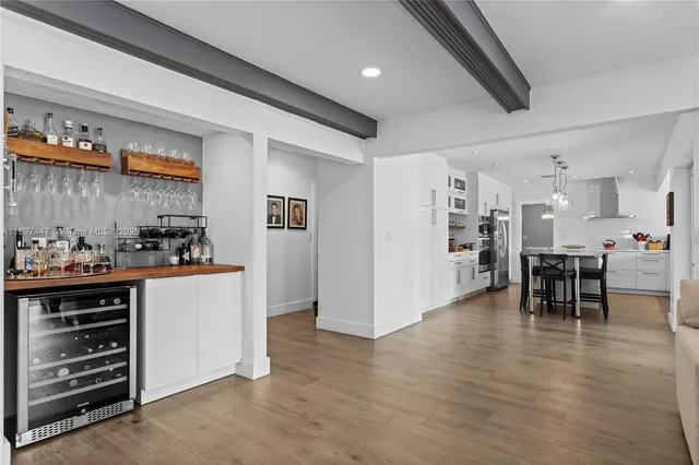 a kitchen with stainless steel appliances a dining table chairs refrigerator and cabinets
