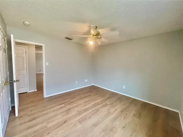 an empty room with wooden floor fan and window