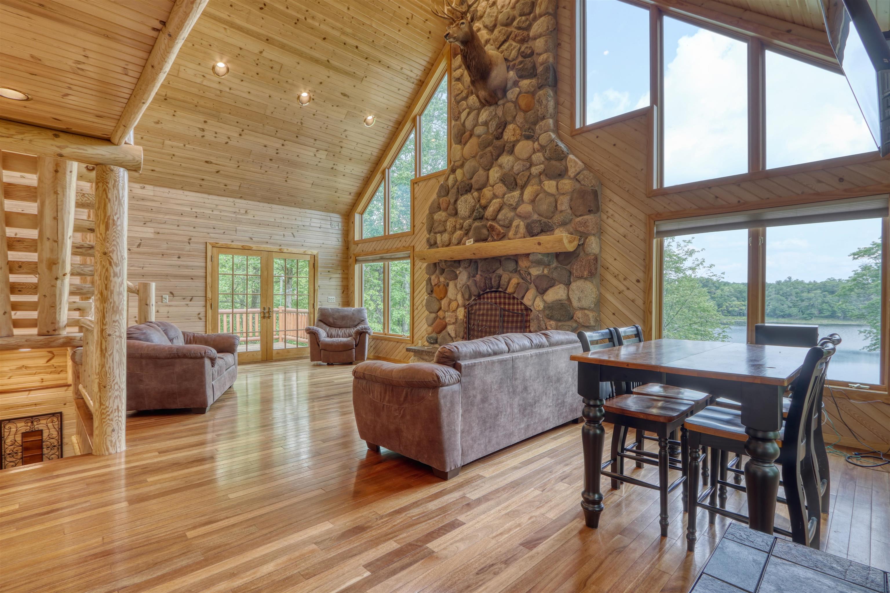 1881 County Road A Spooner, WI 54801 - Photo 20 of 54 Living area featuring high vaulted ceiling, light wood finished floors, wooden walls, wooden ceiling, and a fireplace