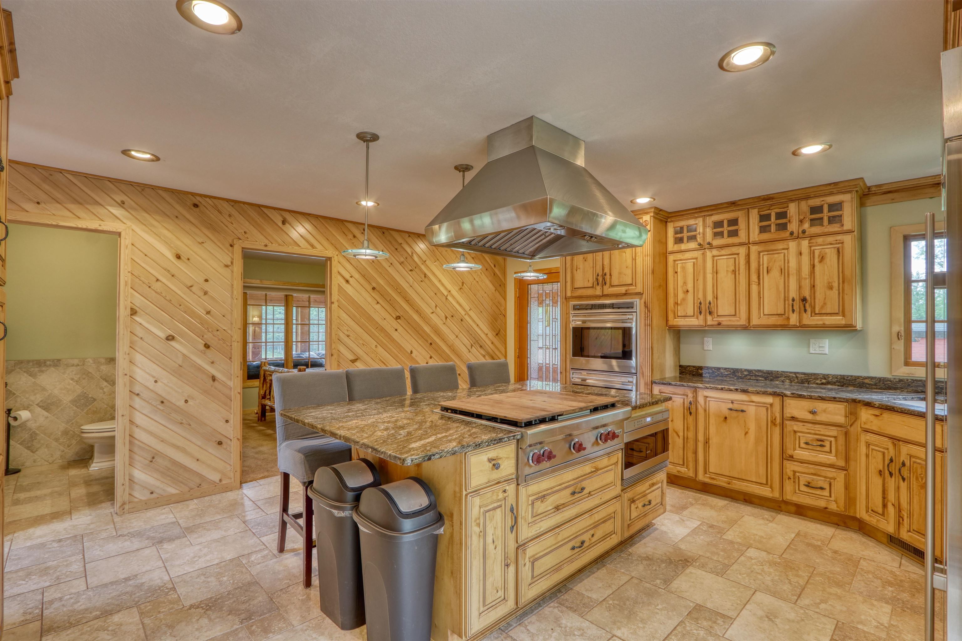1881 County Road A Spooner, WI 54801 - Photo 27 of 54 Kitchen with island exhaust hood, wooden walls, stone tile floors, appliances with stainless steel finishes, and a breakfast bar
