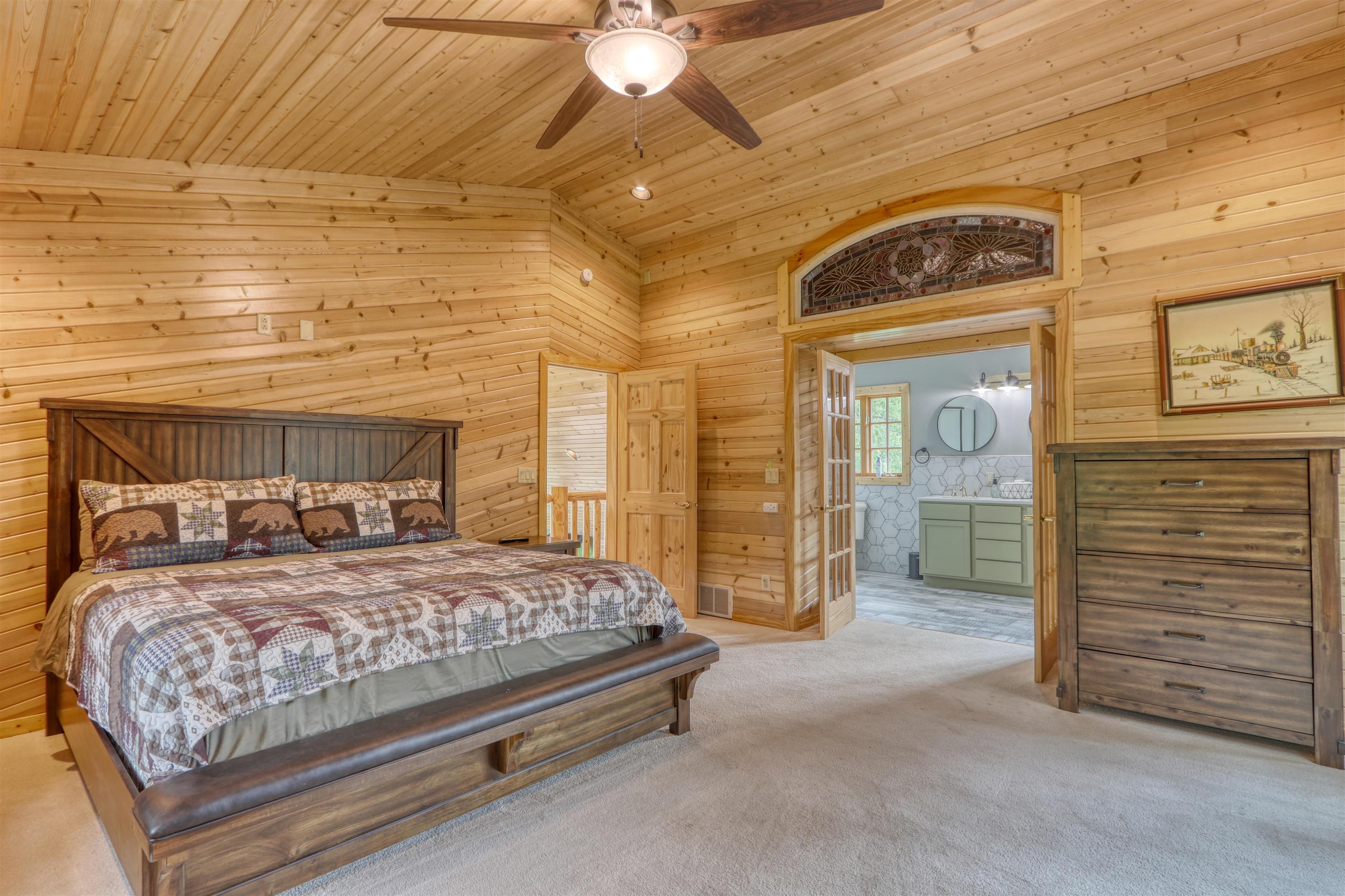 1881 County Road A Spooner, WI 54801 - Photo 34 of 54 Carpeted bedroom with wood ceiling, wood walls, ensuite bathroom, lofted ceiling, and ceiling fan