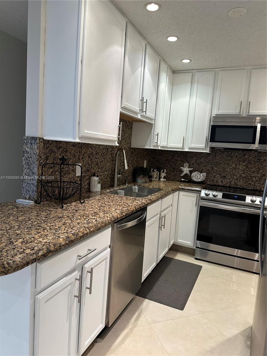 6600 Northeast 22nd Way, Unit 2304 Fort Lauderdale, FL 33308 - Photo 4 of 11 a kitchen with granite countertop a sink a stove and cabinets