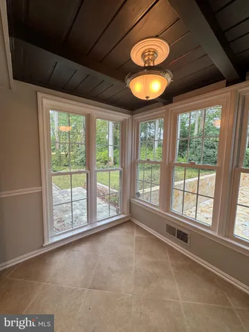 a view of an empty room with wooden floor and fan