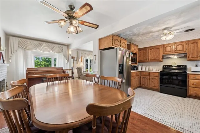 a kitchen with stainless steel appliances granite countertop a stove a refrigerator a kitchen island a dining table and chairs with wooden floor