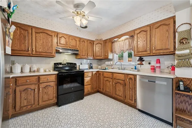 a kitchen with granite countertop a sink cabinets stainless steel appliances and a window