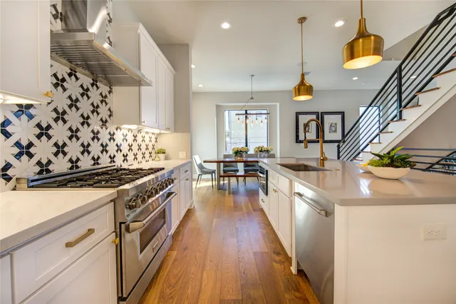 a kitchen with stainless steel appliances a stove a sink a chimney wooden floor and cabinets
