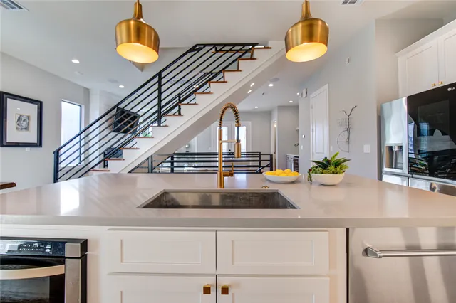 a kitchen with stainless steel appliances granite countertop a kitchen island a stove a refrigerator and a sink