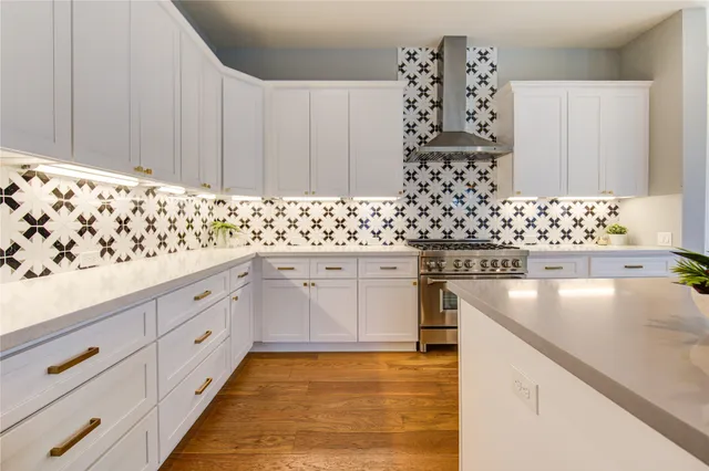 a kitchen with granite countertop a stove a sink a dining table and chairs with wooden floor