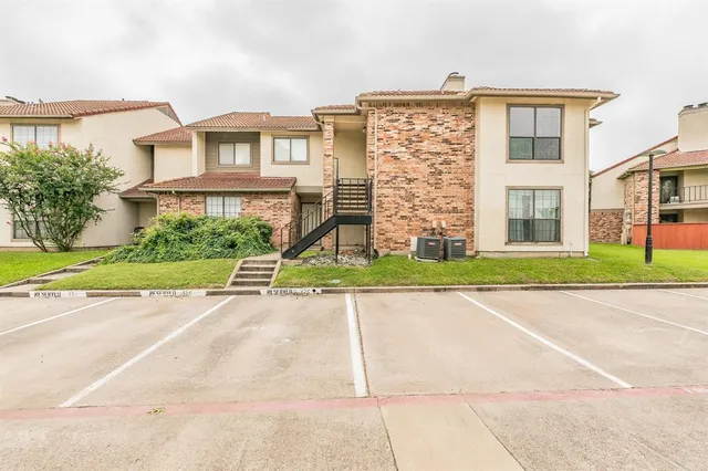 front view of a brick house next to a yard with large trees
