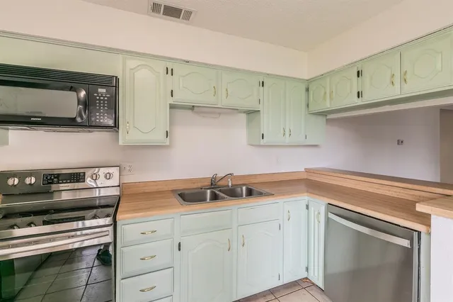 a kitchen with cabinets stainless steel appliances and wooden floor