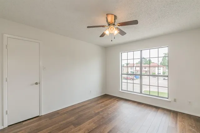 an empty room with wooden floor fan and windows