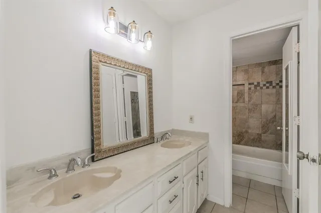 a bathroom with a granite countertop sink mirror and a bathtub