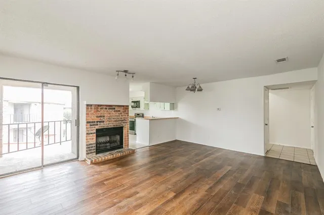 an empty room with wooden floor fireplace and windows