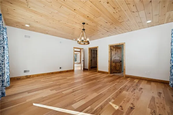 a view of an empty room with wooden floor and windows
