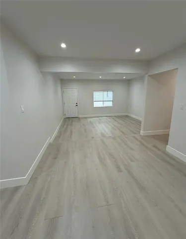 an empty room with wooden floor and window