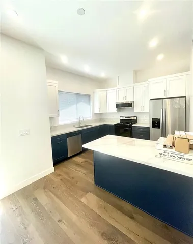a large white kitchen with kitchen island sink and refrigerator
