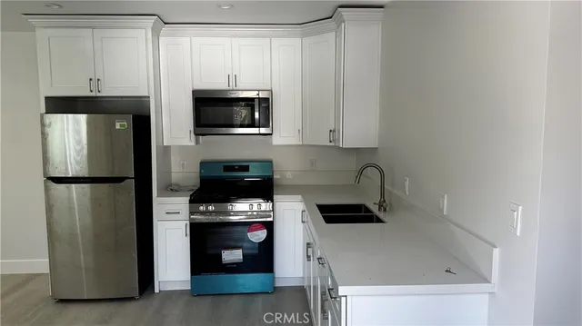 a kitchen with stainless steel appliances granite countertop a refrigerator stove and white cabinets