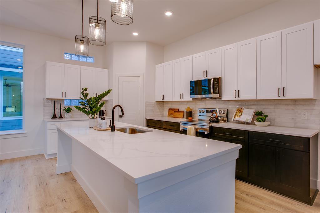 2130 Shea Road, Unit 1002 Dallas, TX 75235 - Photo 12 of 39 Kitchen featuring white cabinetry, a kitchen island with sink, sink, and appliances with stainless steel finishes