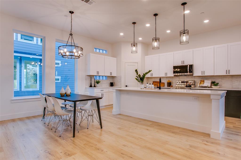 2130 Shea Road, Unit 1002 Dallas, TX 75235 - Photo 2 of 39 Kitchen featuring white cabinets, an island with sink, stainless steel appliances, and decorative light fixtures