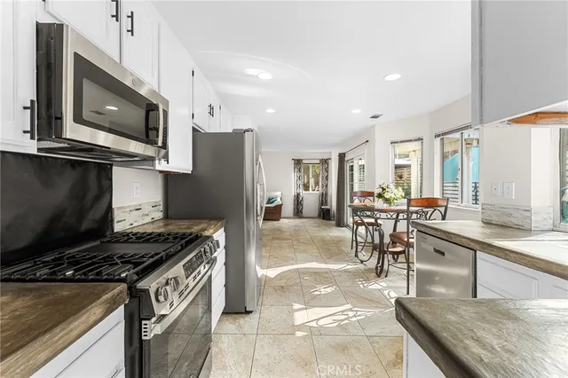 a kitchen with stainless steel appliances granite countertop a stove top oven a sink a dining table and chairs