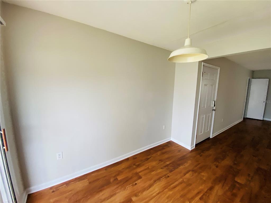 2757 L B McLeod Road, Unit C Orlando, FL 32805 - Photo 13 of 23 an empty room with wooden floor and chandelier