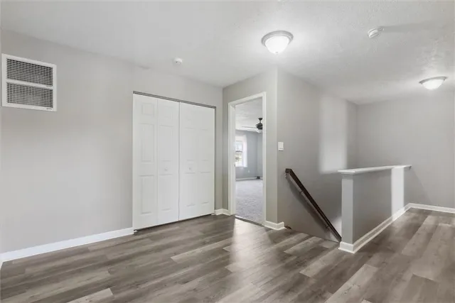 a view of an empty room with wooden floor and a ceiling fan