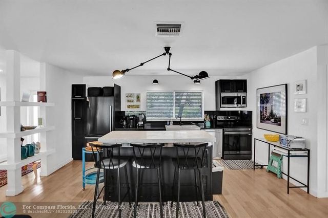 a kitchen with stainless steel appliances granite countertop a stove refrigerator and a dining table with wooden floor